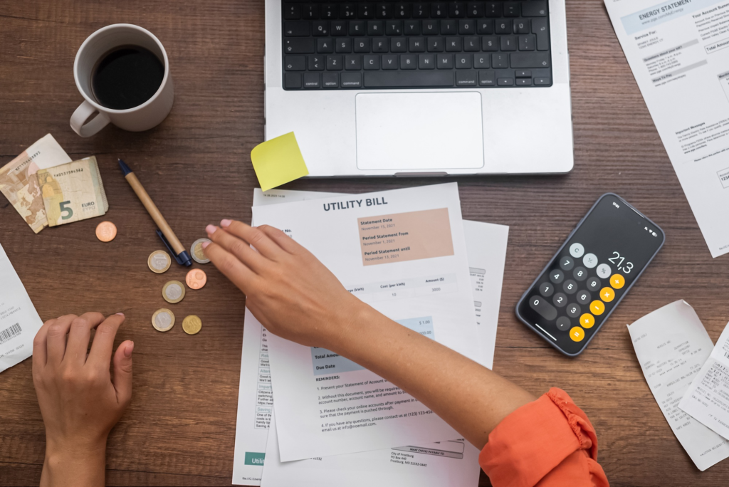 Businesswoman counts money sitting at table with bank account with prices and calculator with number
